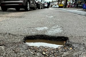 street-with-pothole-potholes-300x200.jpg